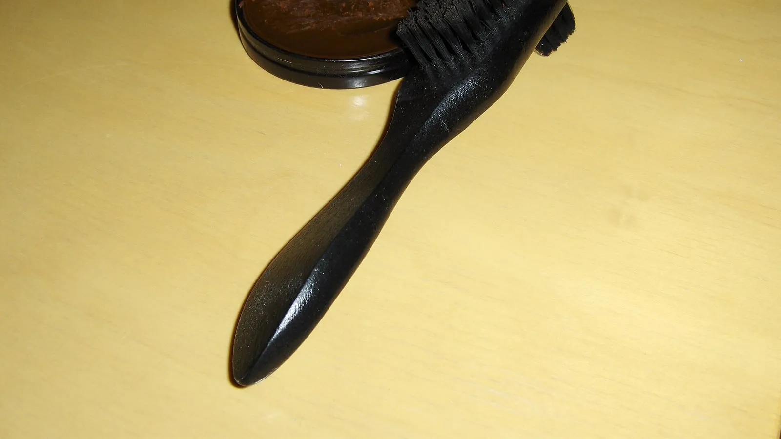 A shoe brush and a tin of polish on a bench